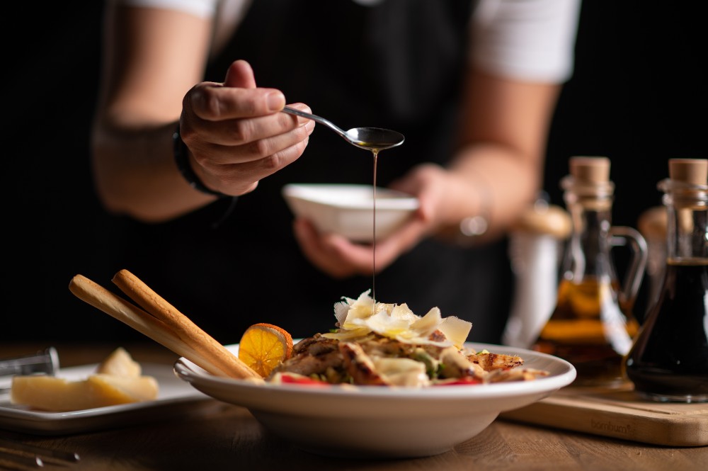 A female chef pouring souce on salad