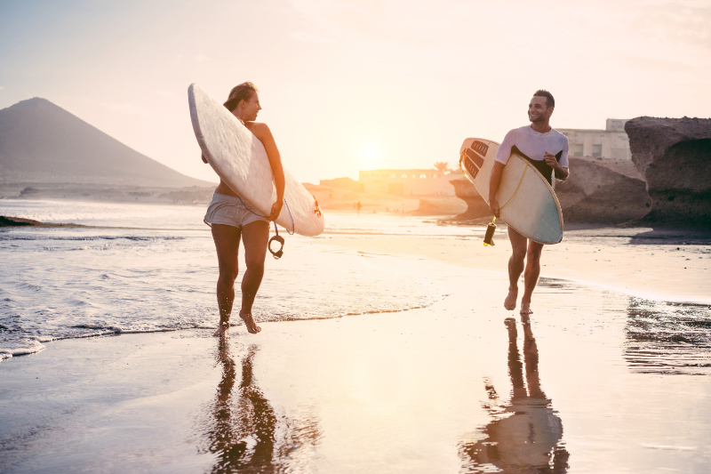 Surfers couple running with surf boards on the beach