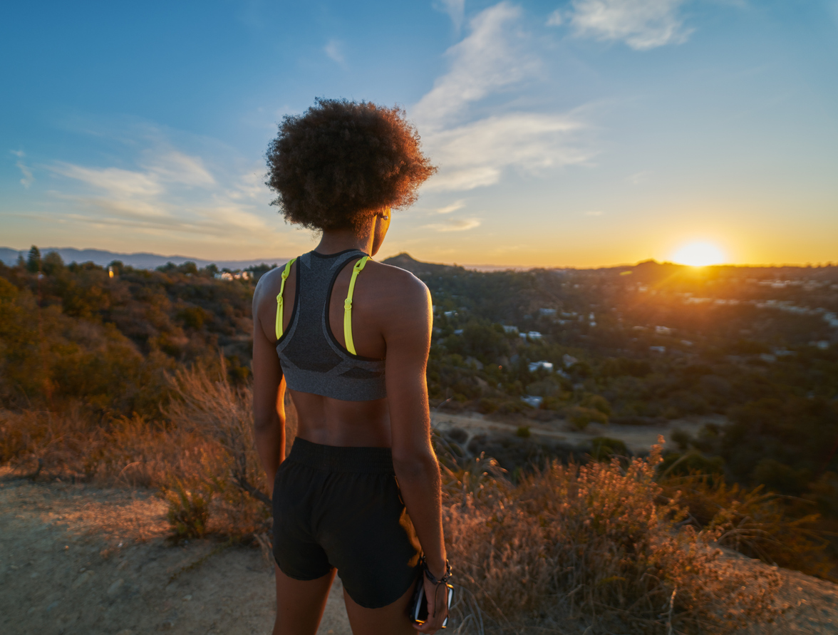 african american woman watching sunset while resting after hike at runyon canyon wearing athletic clothes